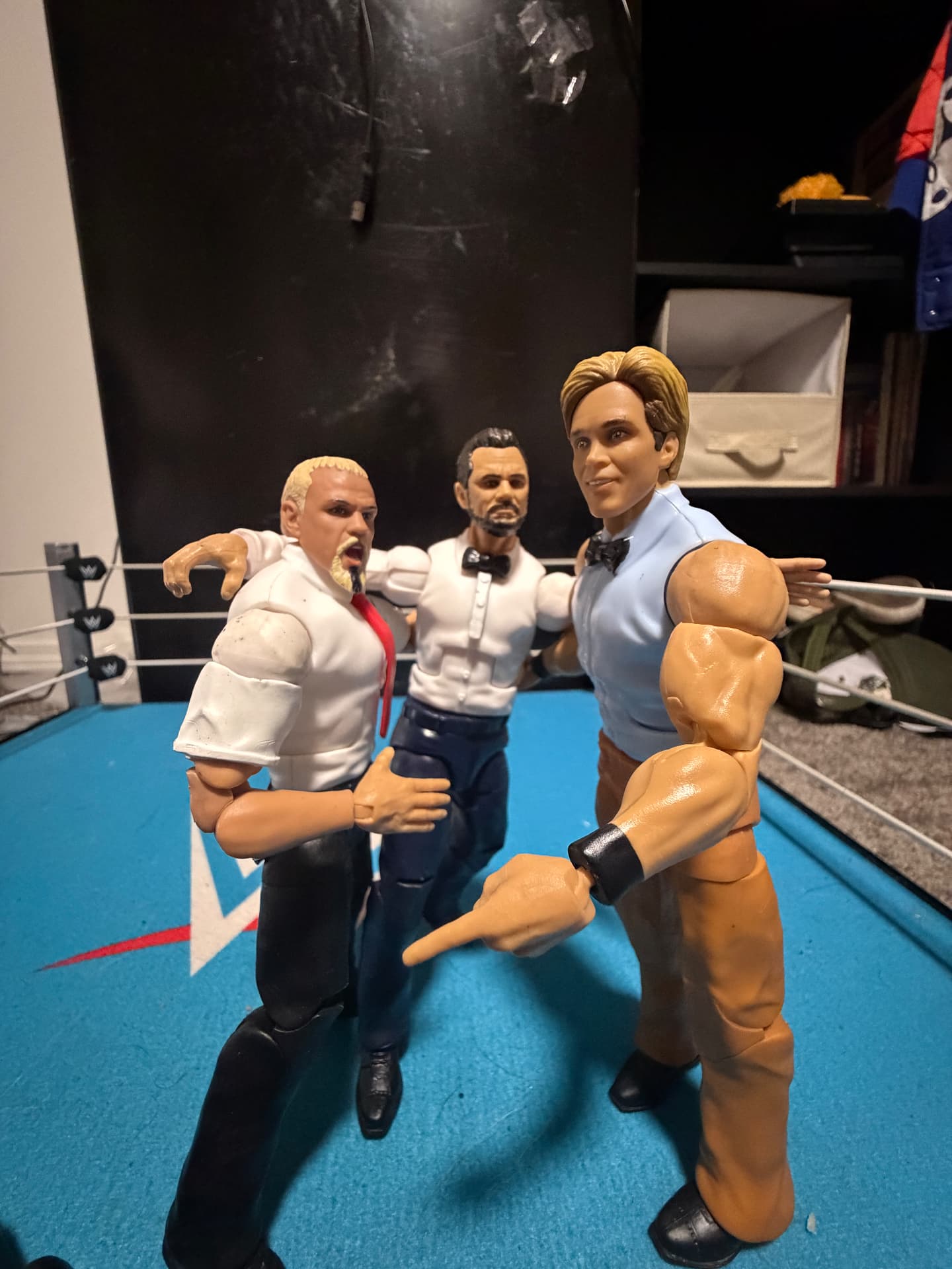 Three figures gathered in the wrestling ring